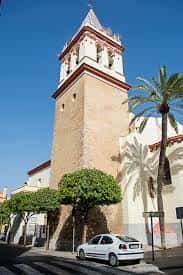 Torre de la iglesia de San Gil Abad con palmeras y cielo azul en primer plano