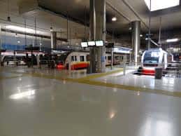 Vista interior de la estación intermodal con trenes en andenes y suelo brillante