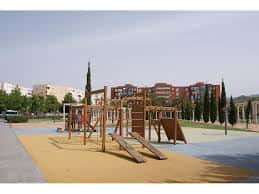 Zona de juegos infantiles con estructuras de madera y suelo de seguridad