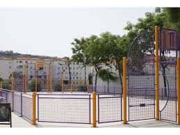 Cancha de baloncesto con valla perimetral y árboles alrededor
