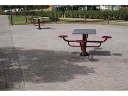 Mesa de picnic metálica en zona pavimentada del parque