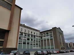 Fachada lateral del colegio con estacionamiento y cielo nublado