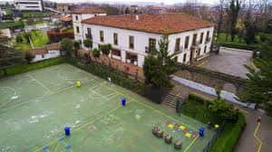 Patio deportivo del colegio con cancha verde y edificios adyacentes