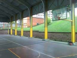 Pista de baloncesto cubierta con estructura metálica y columnas amarillas