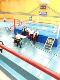 Gimnasio interior con ring de boxeo y actividad deportiva