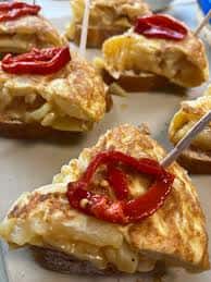 Plato de pinchos o tapas con pimiento rojo y base de tortilla o pan