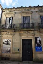 Entrada de la fundación con cartel azul de homenaje a Torrente Ballester y ventanales decorativos