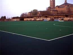 Campo de fútbol sintético del Complejo Deportivo Universidad Laboral con el edificio histórico al fondo