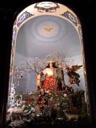 Imagen de la Divina Pastora en su altar, rodeada de flores y decoración religiosa
