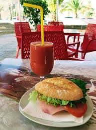 Plato de hamburguesa y bebida en terraza del Bar El Parque