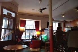Interior acogedor del bar con ventanas, cortinas rojas y ambiente cálido