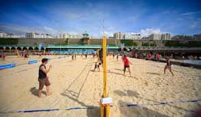 Vista general de la cancha de voleibol en la playa con jugadores en acción
