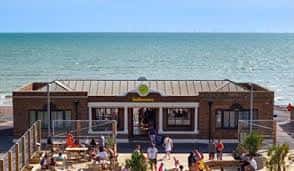 Fachada del Yellowave Beach Sports Venue frente al mar con visitantes