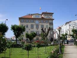 Vista exterior de la Subdelegación del Gobierno en A Coruña con jardín y bandera española