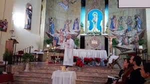 Ceremonia religiosa en el altar principal del santuario con sacerdote y decoración floral