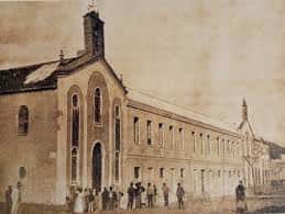 Vista histórica del Santuario de María Auxiliadora en Málaga con grupo de personas frente al edificio