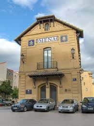 Vista exterior del Edificio Italcable en Málaga con fachada amarilla y letrero 'EMENAC'