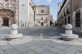 Plaza frente al monasterio con bolardos de piedra y fachadas históricas