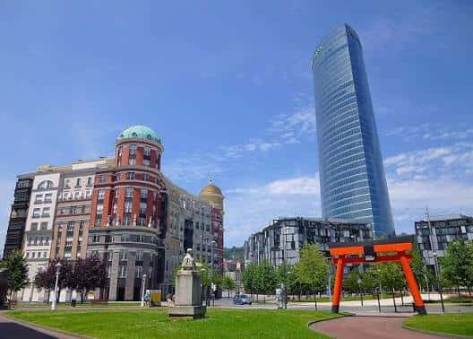 Plaza Euskadi con el Torre Iberdrola, edificios históricos y una escultura roja en primer plano