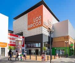 Fachada exterior del Centro Comercial Los Arcos con señalización naranja y entrada principal