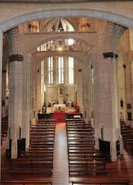Interior de la nave principal con bancos de madera y altar iluminado