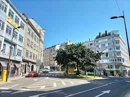 Vista diurna de la Praza do Barrio das Flores en Vigo, con edificios residenciales y árboles en el centro