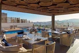 Área de comedor al aire libre con techo de madera y vista a la piscina y montañas