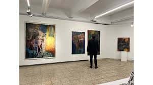 Interior de la galería con visitantes observando las obras