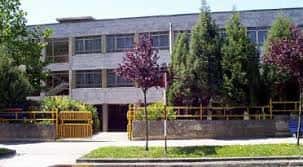 Vista exterior de la fachada de la Facultad de Medicina con árboles y valla amarilla