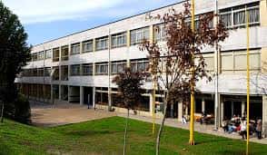 Fachada lateral de la Facultad de Medicina con patio y estudiantes sentados
