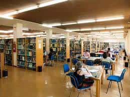 Interior de la biblioteca de la Facultad de Medicina con estanterías y mesas de estudio