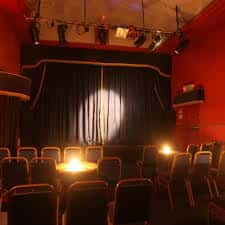 Interior del auditorio del Rialto Theatre con butacas y escenario iluminado
