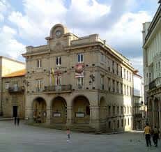 Fachada principal del Ayuntamiento de Ourense en la plaza, con arquitectura clásica y banderas