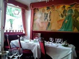 Interior elegante del restaurante con mesa servida y mural histórico en la pared