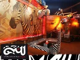 Área de lounge con mobiliario estampado de cebra y murales de animales en la pared