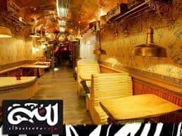 Pasillo interior del local con mesas de madera y iluminación ambiental dorada