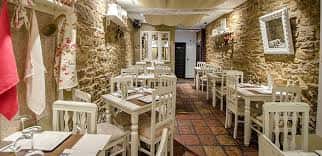 Interior del comedor con mesas blancas y paredes de piedra rústica