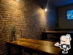 Área de mesas en el bar Chester con pared de ladrillo y ambiente acogedor