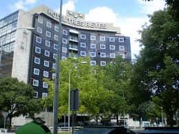 Edificio del Hotel Tres Reyes desde la calle, con árboles y tráfico en primer plano