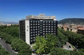 Vista aérea del hotel con entorno urbano y montañas al fondo