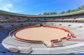 Vista panorámica del interior de la Plaza de Toros de Pamplona con la arena vacía y gradas bajo un cielo despejado
