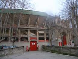Fachada exterior de la Plaza de Toros de Pamplona con árboles sin hojas y entrada principal
