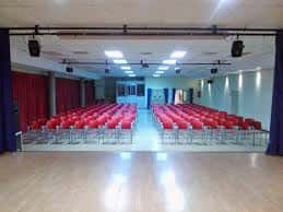 Sala de eventos con butacas rojas dispuestas para conferencias o espectáculos