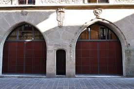 Detalle de los arcos de entrada de la Casa del Cordón, con puertas de madera y escudos decorativos sobre los arcos