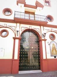 Entrada principal de la capilla con puerta de madera ornamentada y balcón superior