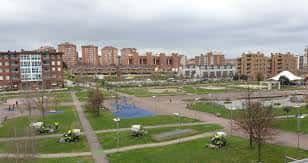 Vista aérea del parque con zonas de juego y edificios al fondo