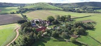 Vista aérea de Sullington Manor Farm rodeada de campos verdes y colinas
