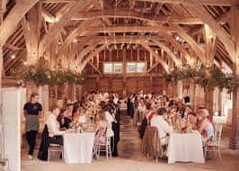 Interior del salón de eventos con techos de vigas de madera y mesas decoradas para una celebración