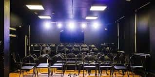 Sala de eventos o teatro del BN1 Arts con sillas dispuestas para audiencia