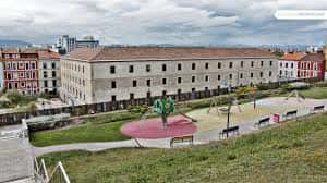 Plaza ajardinada frente a la Tabacalera con zona de juegos infantiles y bancos, ideal para eventos al aire libre
